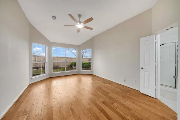a view of empty room with wooden floor and fan