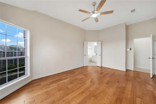 a view of empty room with wooden floor and fan