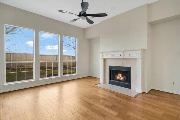 a view of an empty room with wooden floor fireplace and a window