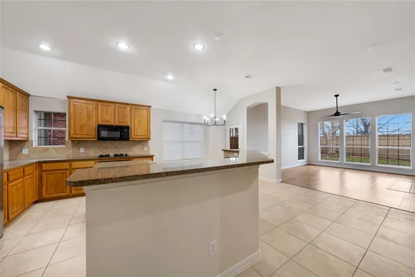 a large kitchen with stainless steel appliances a large counter top a stove a sink a window and a dining table