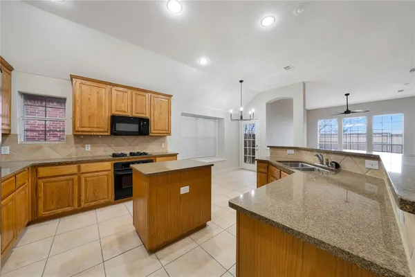 a kitchen with kitchen island granite countertop a sink counter top space appliances and cabinets