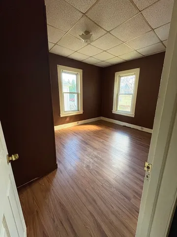 an empty room with wooden floor and windows