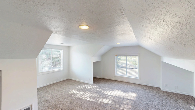 1115 North Main Street Bountiful, UT 84010 - Photo 11 of 17 Spacious room featuring sloped ceilings, two windows with blinds, recessed lighting, and neutral-toned carpeting