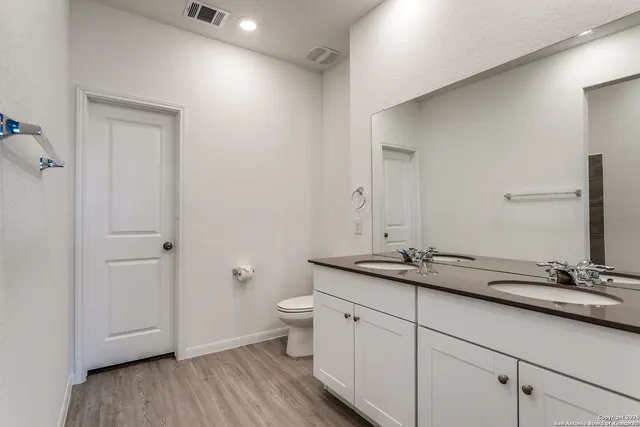 a bathroom with a granite countertop sink toilet and mirror