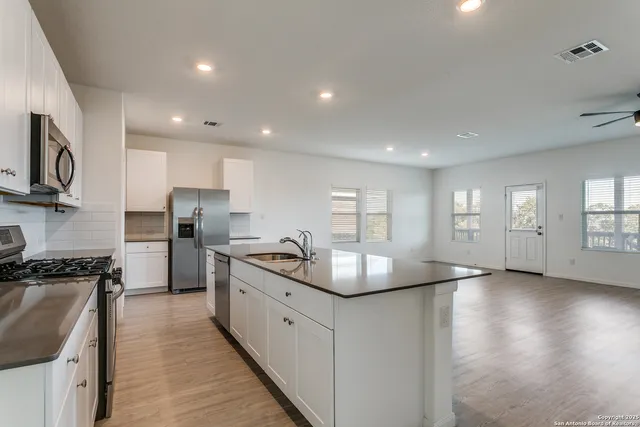 a kitchen with stainless steel appliances granite countertop a sink a stove and a refrigerator