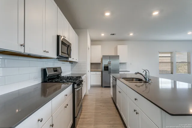 a kitchen with stainless steel appliances a stove a sink a refrigerator and cabinets