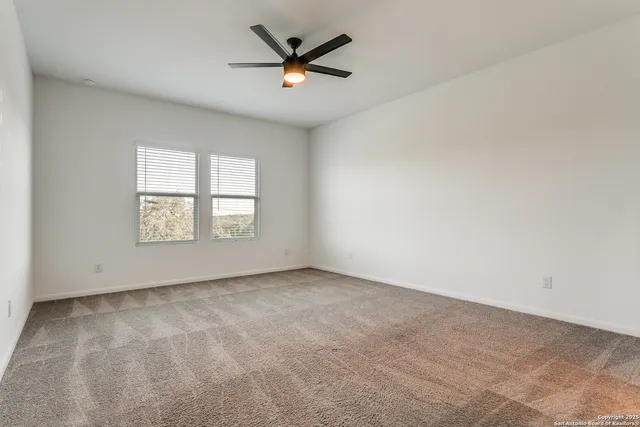 an empty room with windows and ceiling fan
