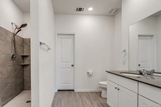a bathroom with a granite countertop toilet a sink and a mirror