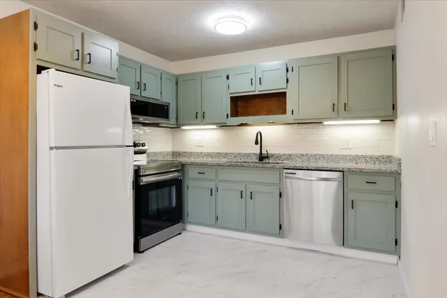 a kitchen with granite countertop cabinets stainless steel appliances and a counter space