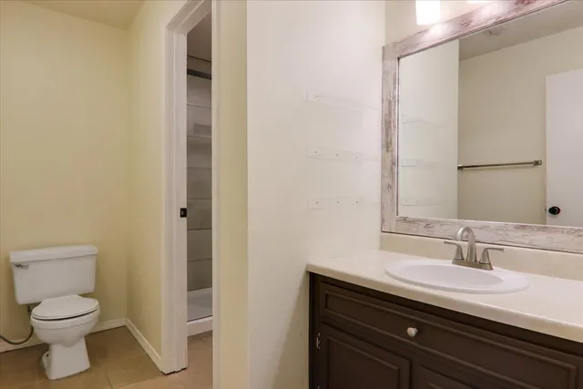 a bathroom with a granite countertop sink a toilet and a mirror