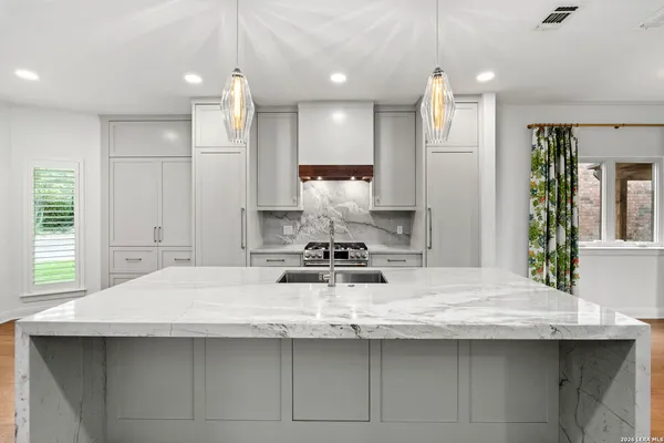 a kitchen with kitchen island granite countertop a sink and white cabinets