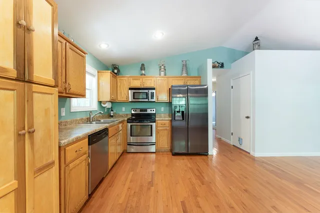 a view of a hallway with wooden floor and a bathroom