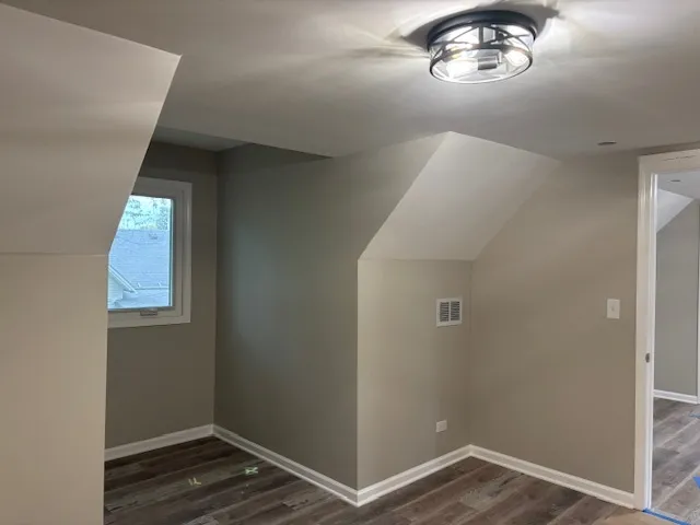 an empty room with wooden floor cabinet and hallway