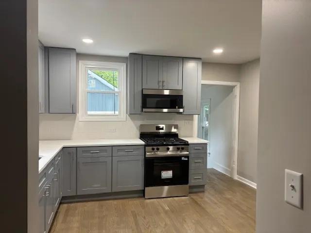 a kitchen with stainless steel appliances granite countertop a stove a sink and a microwave