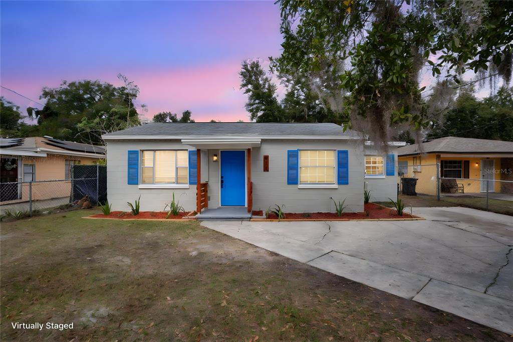 a view of a house with a yard and large tree