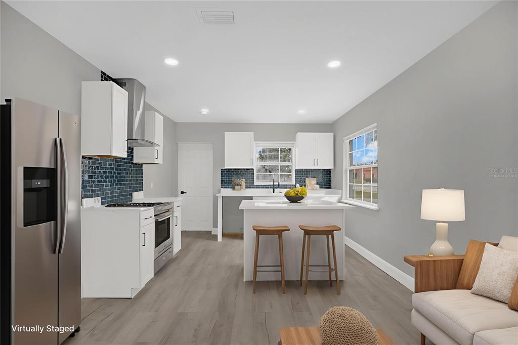 911 Indiana Street Orlando, FL 32805 - Photo 8 of 24 a kitchen with stainless steel appliances a stove a sink a refrigerator white cabinets and wooden floor