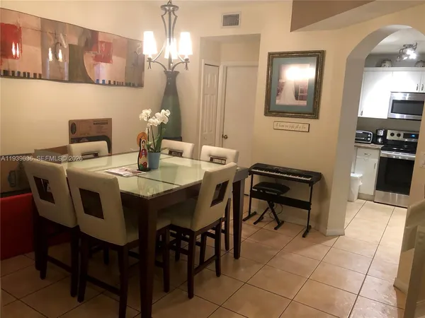 a dining room with stainless steel appliances kitchen island granite countertop a table chairs and a refrigerator