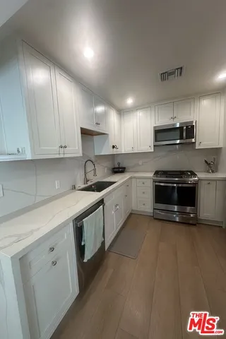 a kitchen with stainless steel appliances granite countertop a stove a sink and a microwave