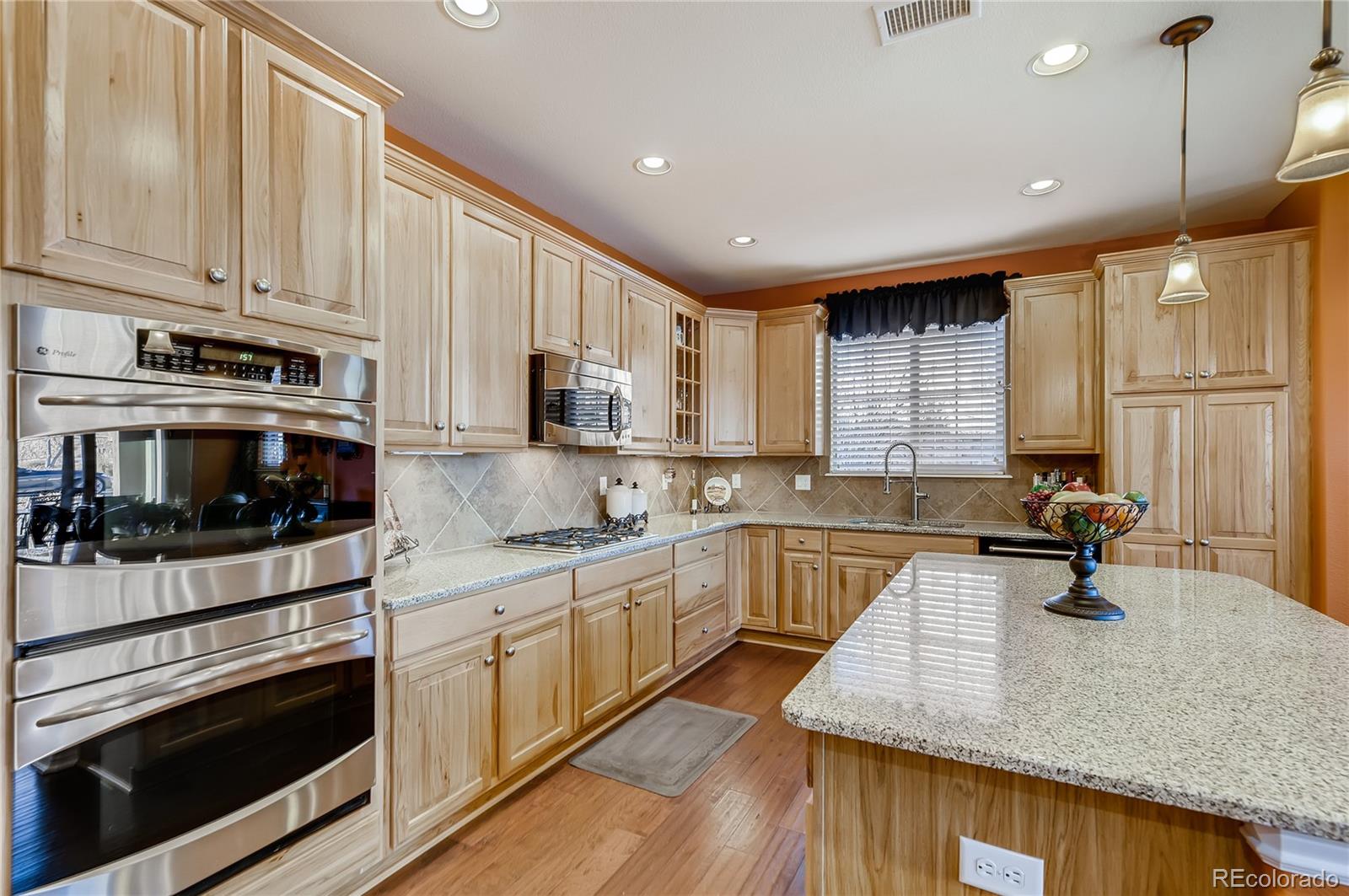 9198 Viaggio Way Highlands Ranch, CO 80126 - Photo 12 of 37 a kitchen with stainless steel appliances white cabinets a sink and a stove