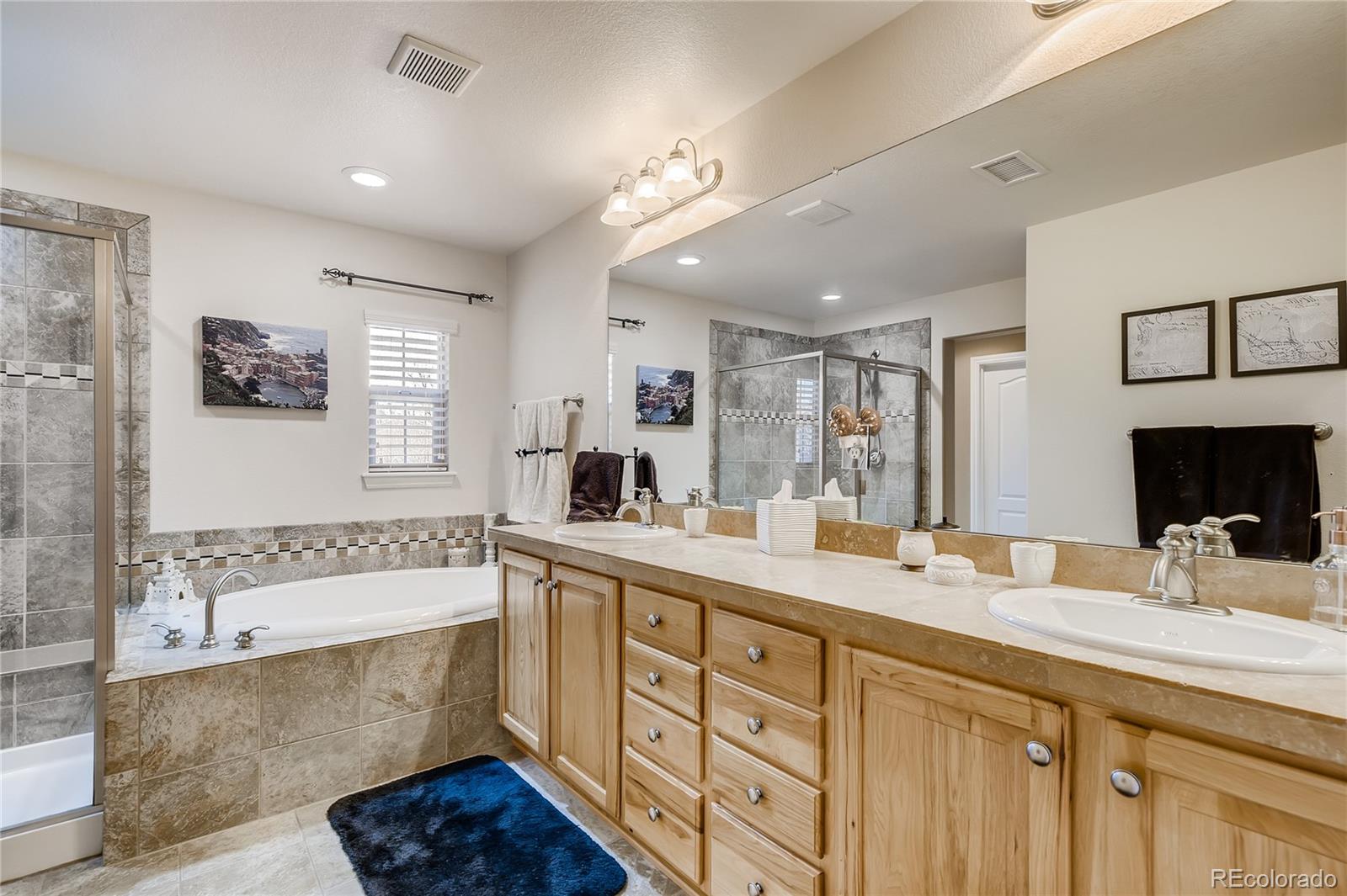 9198 Viaggio Way Highlands Ranch, CO 80126 - Photo 19 of 37 a bathroom with a double vanity sink a mirror a bathtub and next to a window