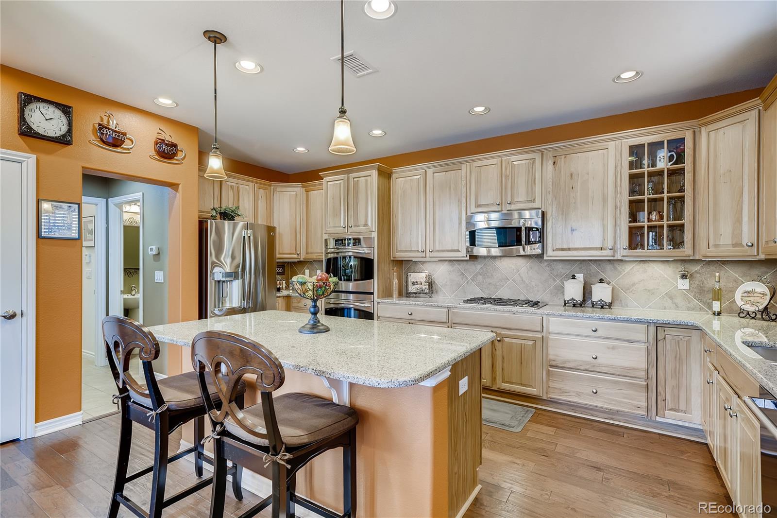 9198 Viaggio Way Highlands Ranch, CO 80126 - Photo 9 of 37 a kitchen with stainless steel appliances granite countertop a sink a stove a refrigerator cabinets and dining table