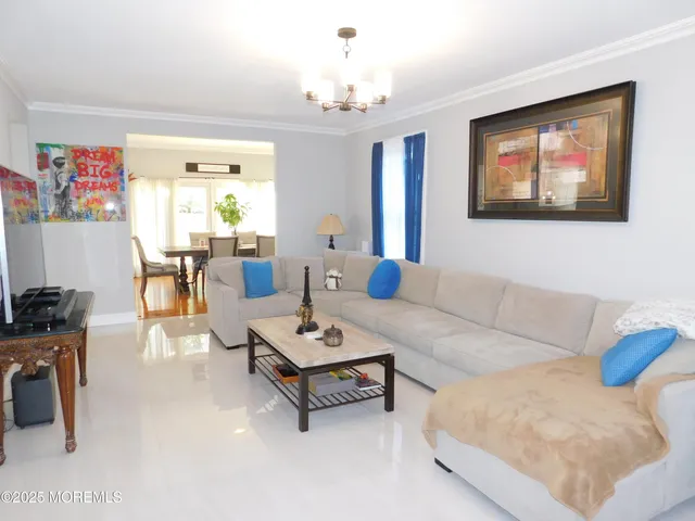 a living room with furniture a chandelier and a dining table