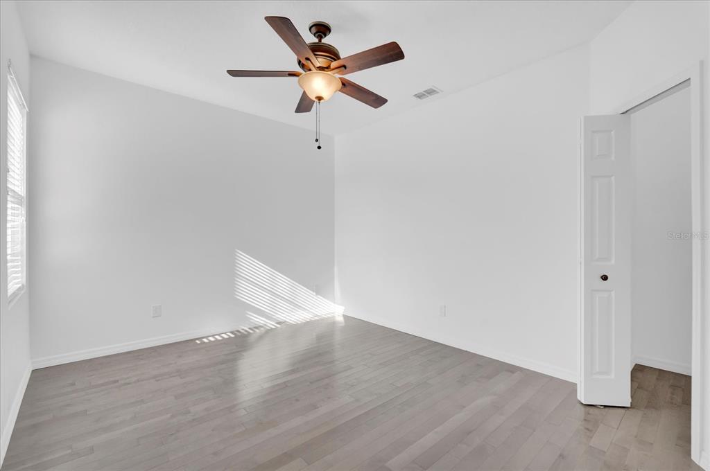 9084 Shepton Street Orlando, FL 32825 - Photo 15 of 26 an empty room with wooden floor a ceiling fan and white walls