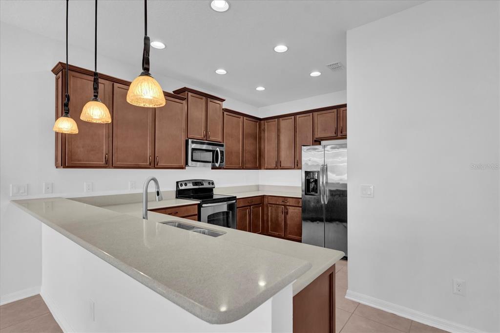 9084 Shepton Street Orlando, FL 32825 - Photo 4 of 26 a kitchen with stainless steel appliances granite countertop a sink a stove and a refrigerator
