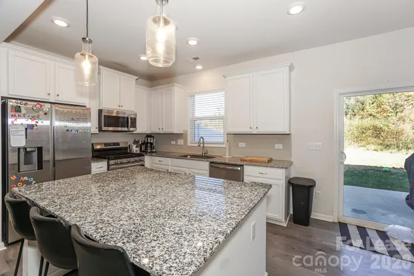 a kitchen with stainless steel appliances granite countertop a sink stove microwave and refrigerator