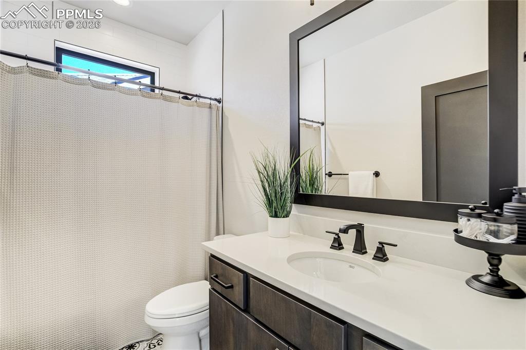 12284 Monarchos Lane Colorado Springs, CO 80921 - Photo 23 of 50 a bathroom with a granite countertop sink toilet a mirror and shower