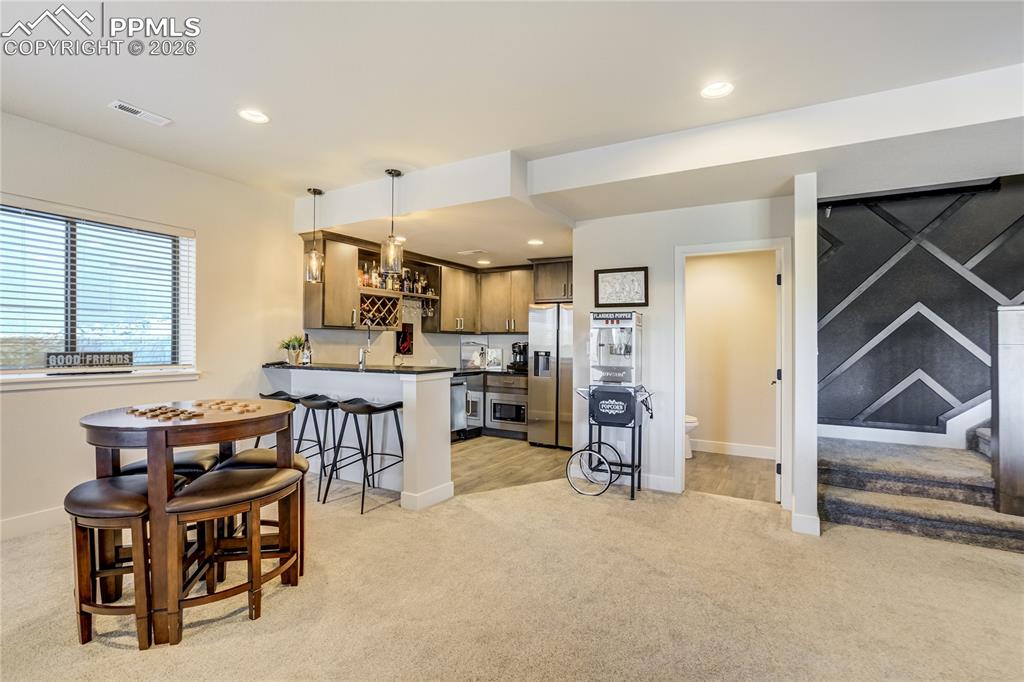 12284 Monarchos Lane Colorado Springs, CO 80921 - Photo 29 of 50 a kitchen with stainless steel appliances kitchen island granite countertop a refrigerator a stove a sink a dining table and chairs with wooden floor