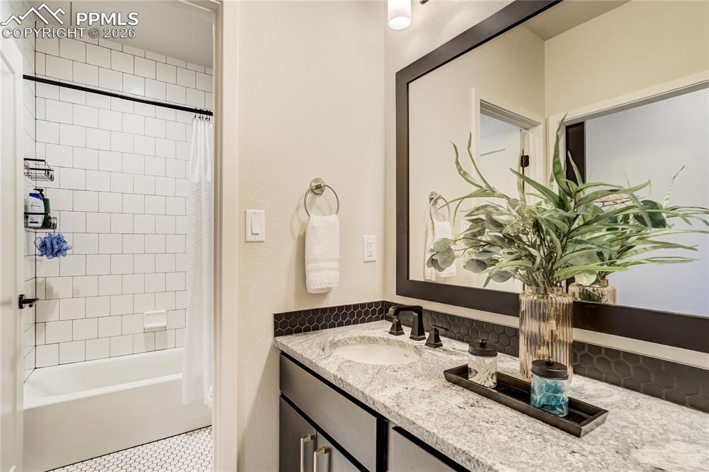 12284 Monarchos Lane Colorado Springs, CO 80921 - Photo 35 of 50 a bathroom with a granite countertop sink a mirror and shower