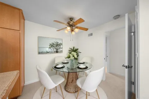 a dining room with furniture and a chandelier fan