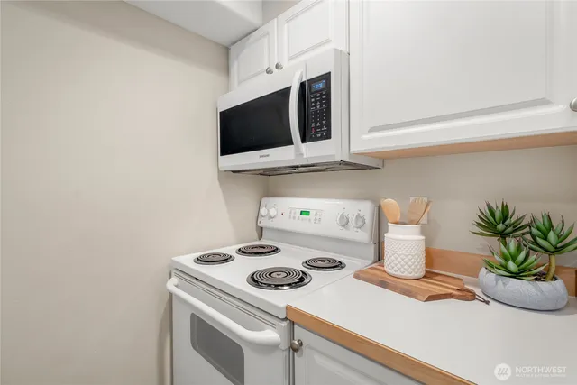 a kitchen with a microwave a stove and a potted plant