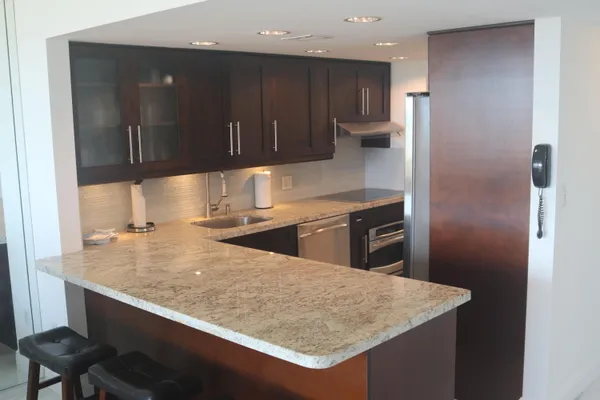 a kitchen with kitchen island granite countertop wooden cabinets and refrigerator