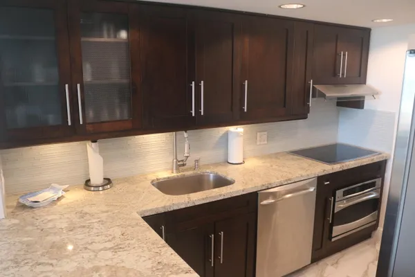a kitchen with granite countertop a sink a stove and cabinets