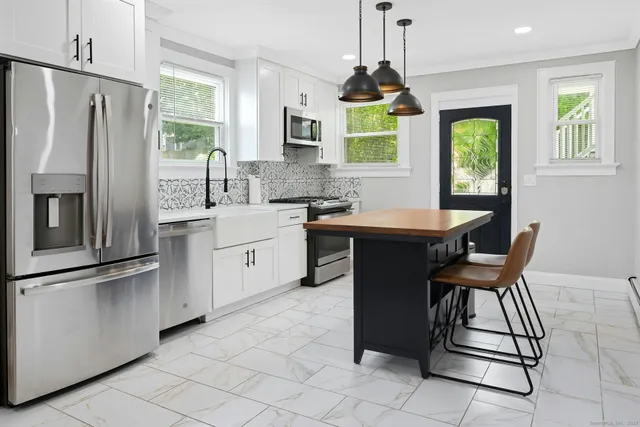 a kitchen with stainless steel appliances granite countertop a stove a sink dishwasher a refrigerator a microwave oven with white cabinets and wooden floor