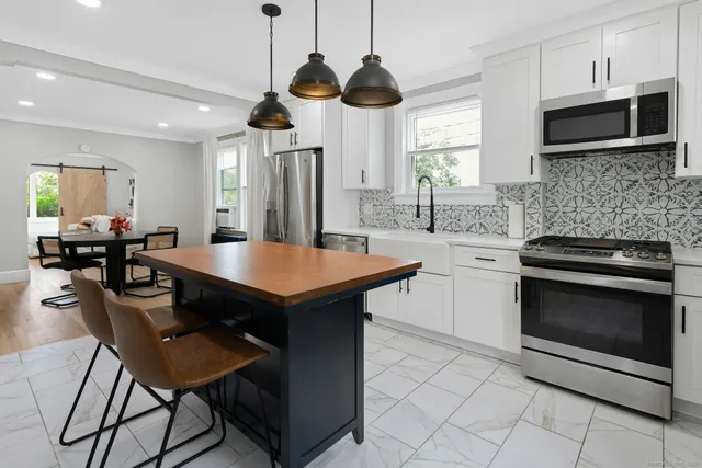 a kitchen with stainless steel appliances a stove a microwave a dining table and chairs