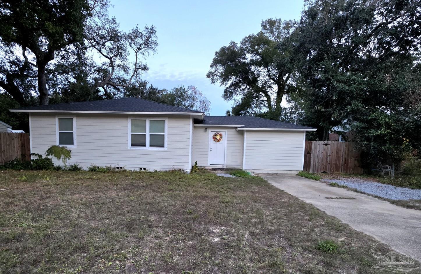 a view of a house with a small yard and a large tree