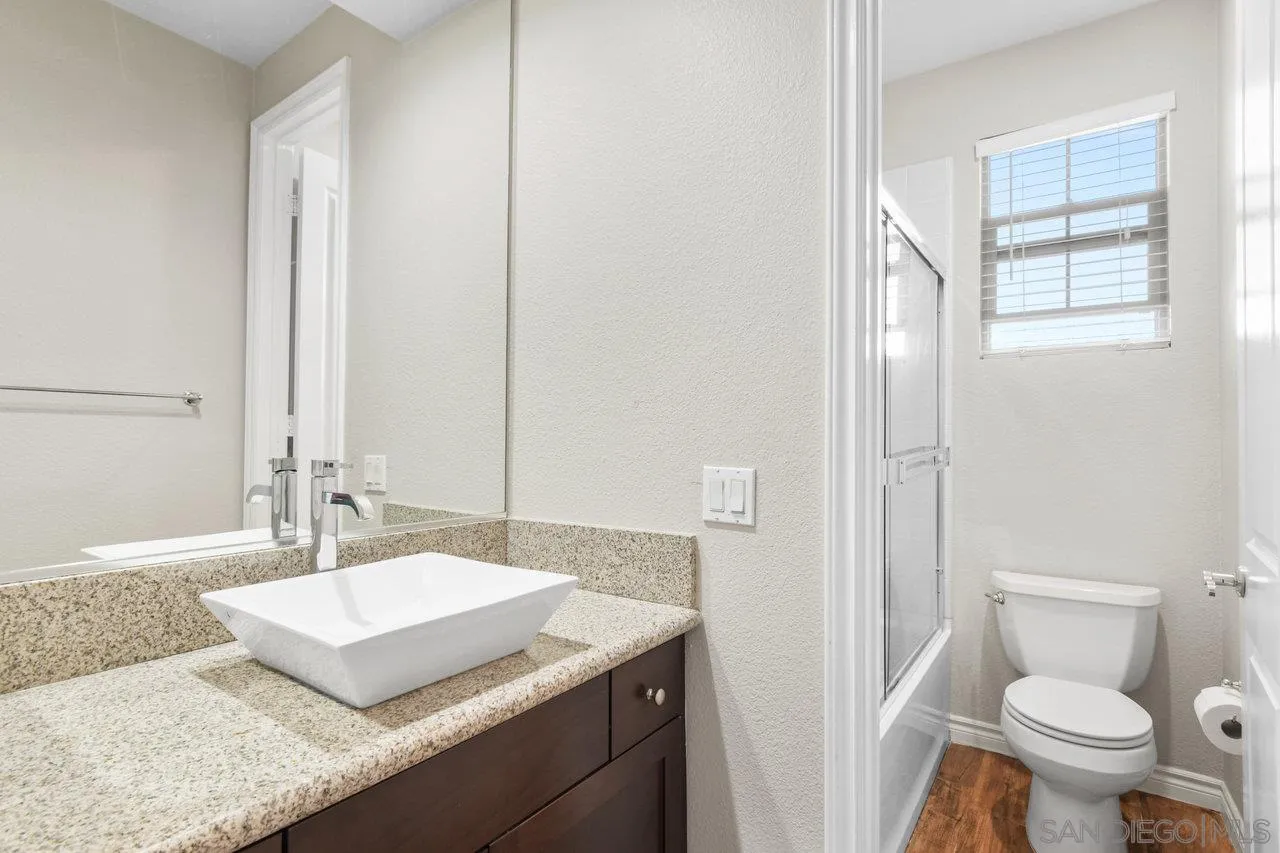 2957 Ranch Gate Road Chula Vista, CA 91914 - Photo 29 of 75 a bathroom with a granite countertop sink a toilet and a mirror