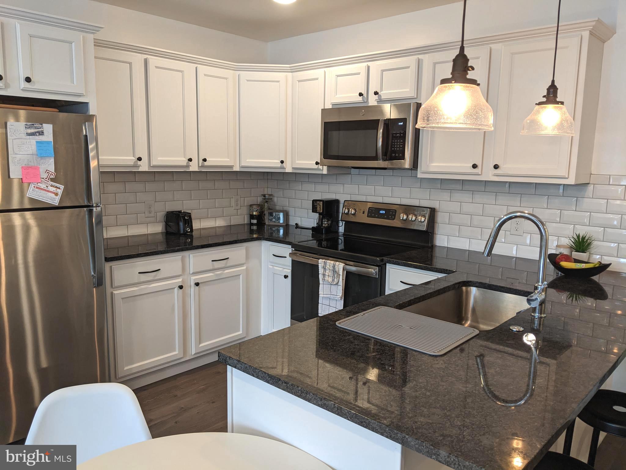 5420 Ridge Avenue, Unit 310 Philadelphia, PA 19128 - Photo 4 of 12 a kitchen with stainless steel appliances granite countertop a sink a stove a microwave a refrigerator a stove and cabinets