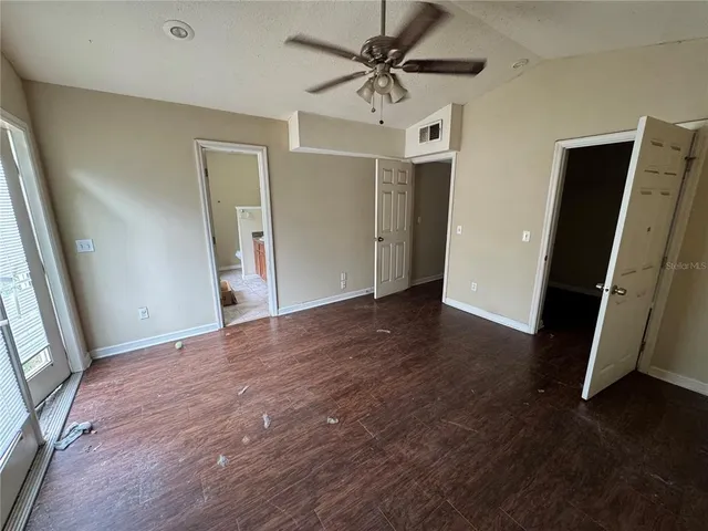an empty room with wooden floor and ceiling fan
