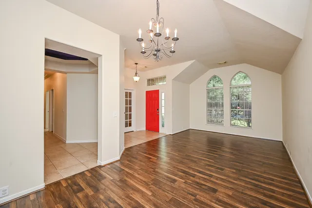 a view of an empty room with window and wooden floor