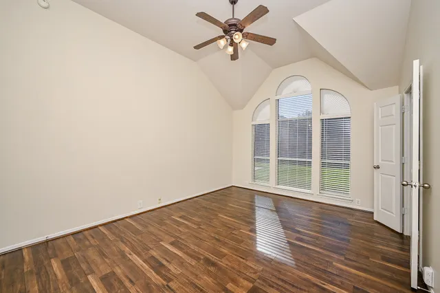 an empty room with wooden floor fan and windows