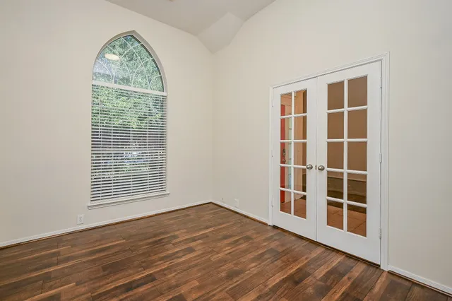 an empty room with wooden floor and windows
