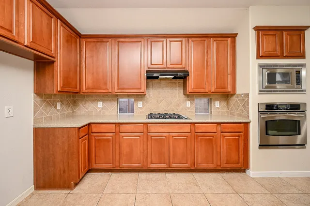 a kitchen with stainless steel appliances granite countertop a stove top oven a refrigerator and cabinets