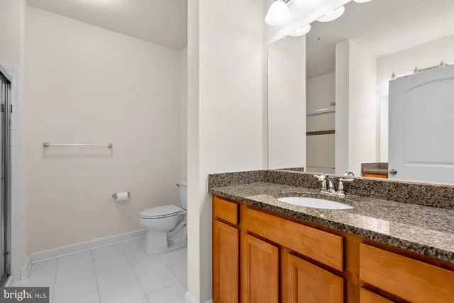 a bathroom with a granite countertop sink a toilet and a mirror