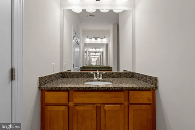 a bathroom with a granite countertop sink a large mirror and a vanity