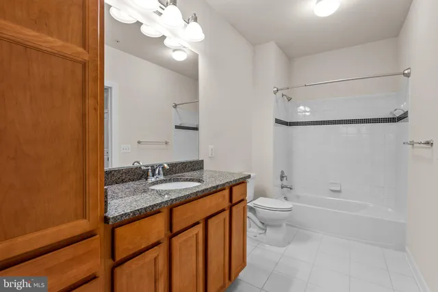 a bathroom with a granite countertop sink a toilet a mirror and shower
