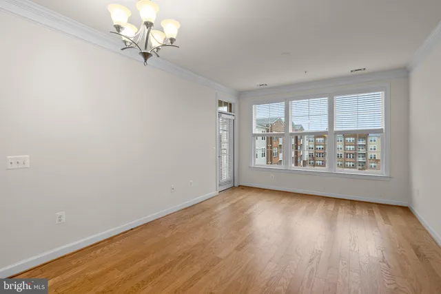 an empty room with wooden floor chandelier fan and windows